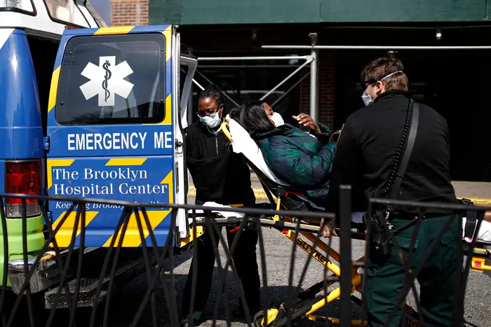 Patient wears a protective face mask as she is unloaded from an ambulance at The Brooklyn Hospital Center emergency room